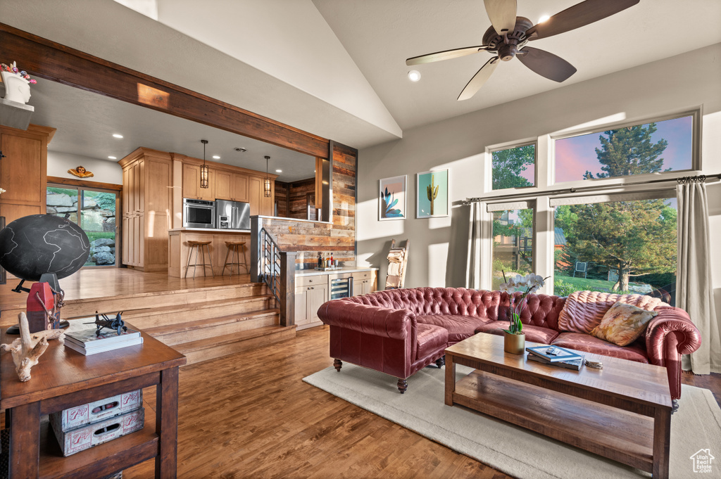 Living area with light wood finished floors, recessed lighting, ceiling fan, and high vaulted ceiling