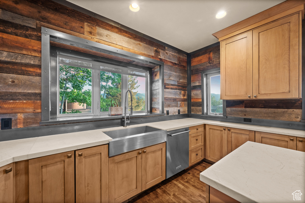 Kitchen featuring a sink, stainless steel dishwasher, dark wood finished floors, wood walls, and recessed lighting