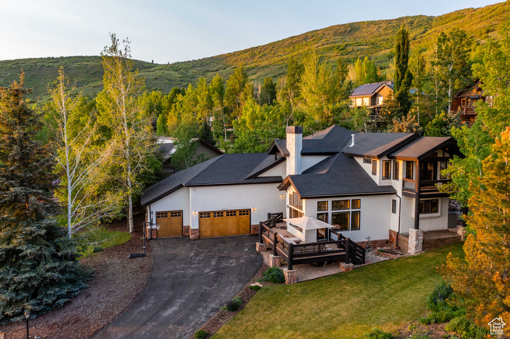 View of front facade featuring a chimney, stucco siding, a front yard, and an attached garage