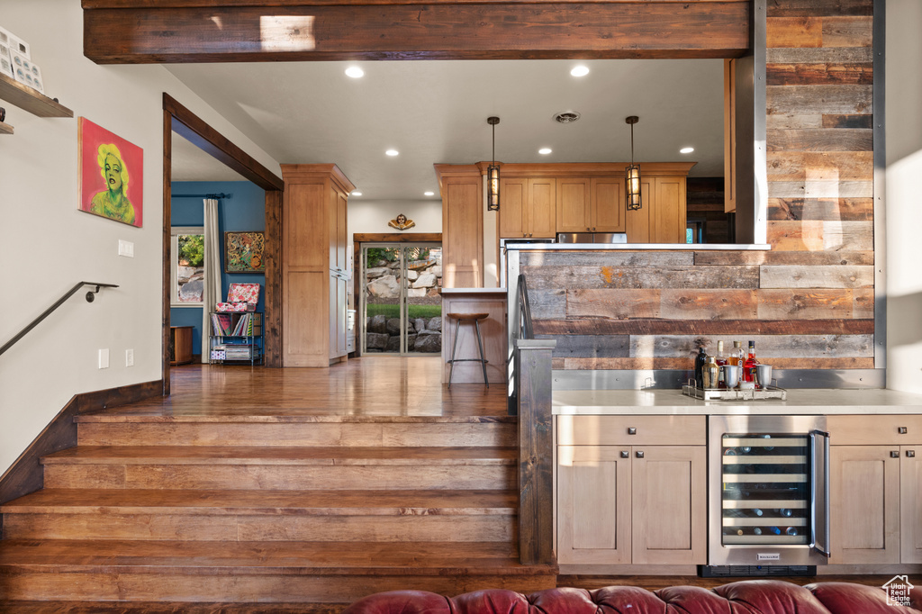 Indoor wet bar featuring wine cooler, recessed lighting, hanging light fixtures, and wood finished floors