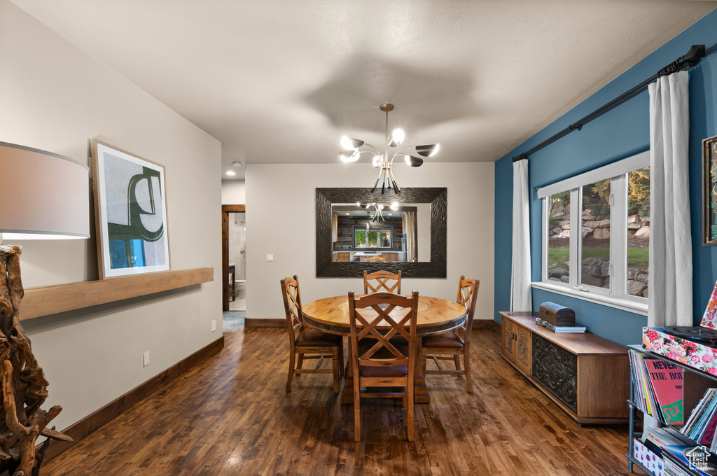 Dining area featuring dark wood-style flooring, a chandelier, and baseboards