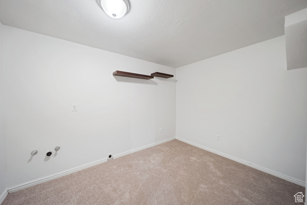 Unfurnished room featuring baseboards and light carpet