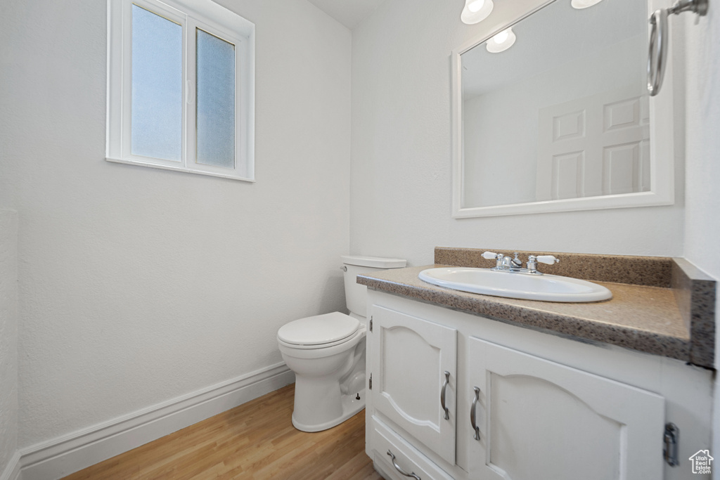 Bathroom featuring vanity, toilet, wood finished floors, and baseboards
