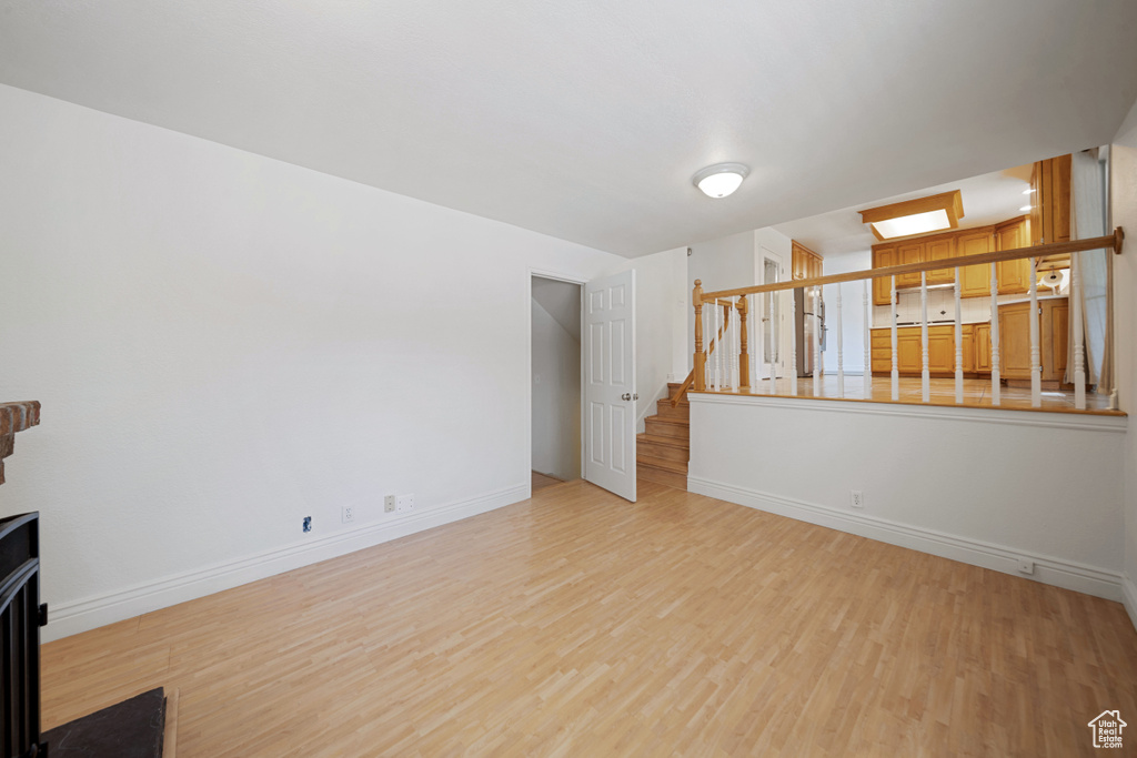 Unfurnished living room featuring wood finished floors, stairs, and baseboards