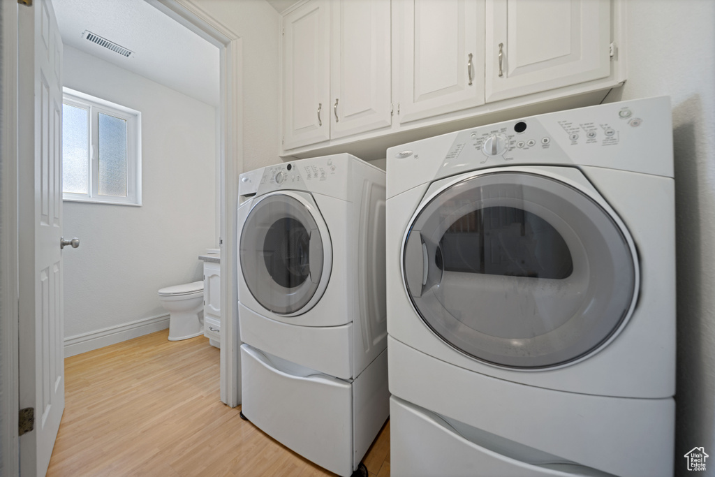 Laundry room with separate washer and dryer, light wood-type flooring, and baseboards