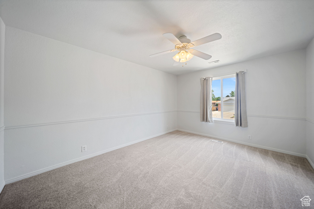 Spare room featuring carpet flooring, baseboards, and a ceiling fan