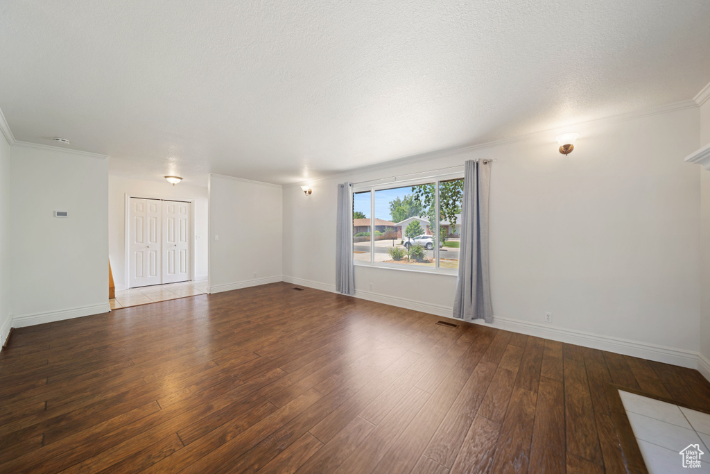 Spare room featuring hardwood / wood-style flooring, baseboards, and crown molding
