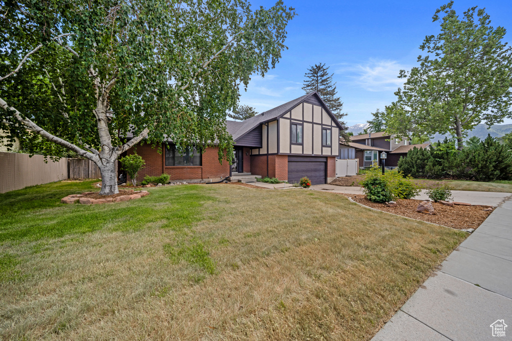 Tudor house with a garage, brick siding, and driveway