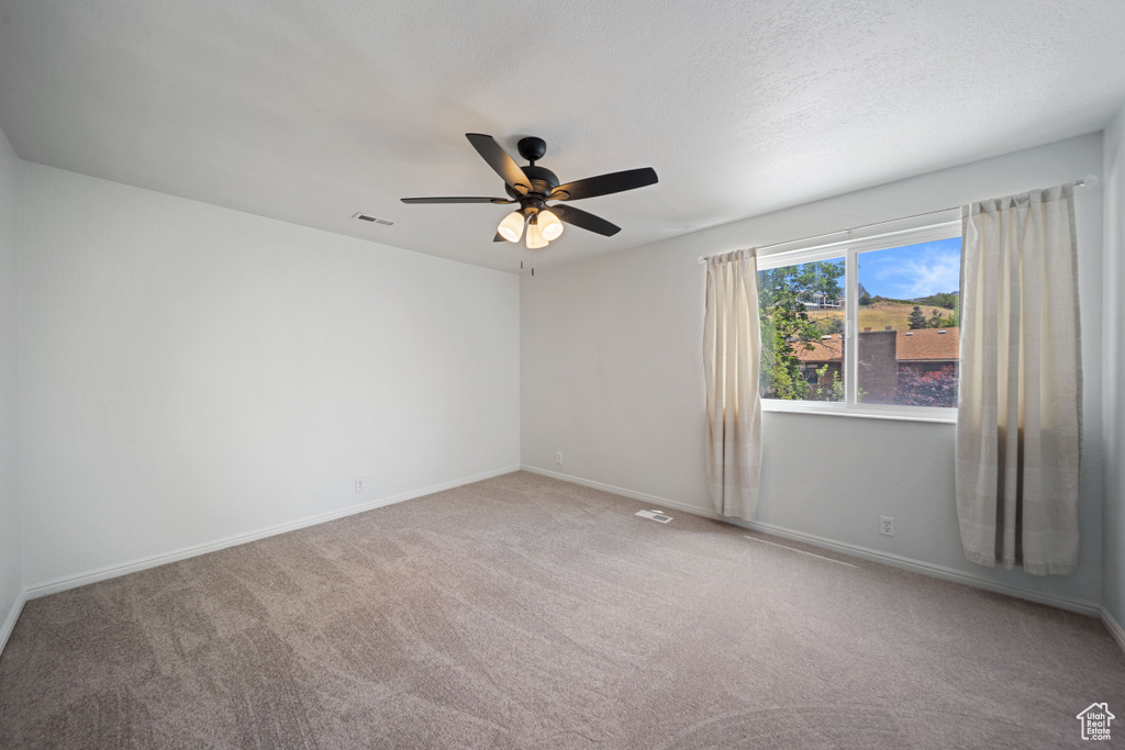 Spare room with ceiling fan, carpet flooring, and baseboards