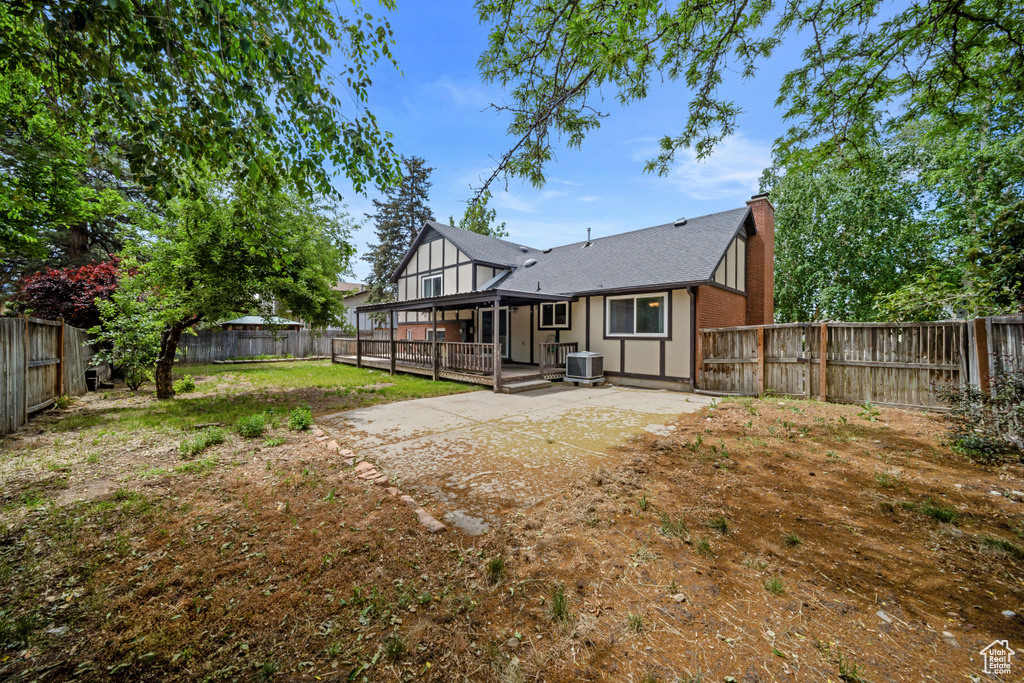 Rear view of property with a fenced backyard, central air condition unit, a chimney, and a patio