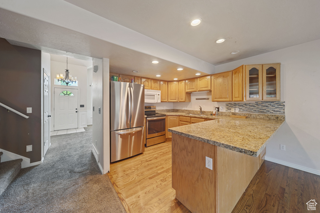 Kitchen with stainless steel appliances, a sink, a peninsula, recessed lighting, and glass insert cabinets