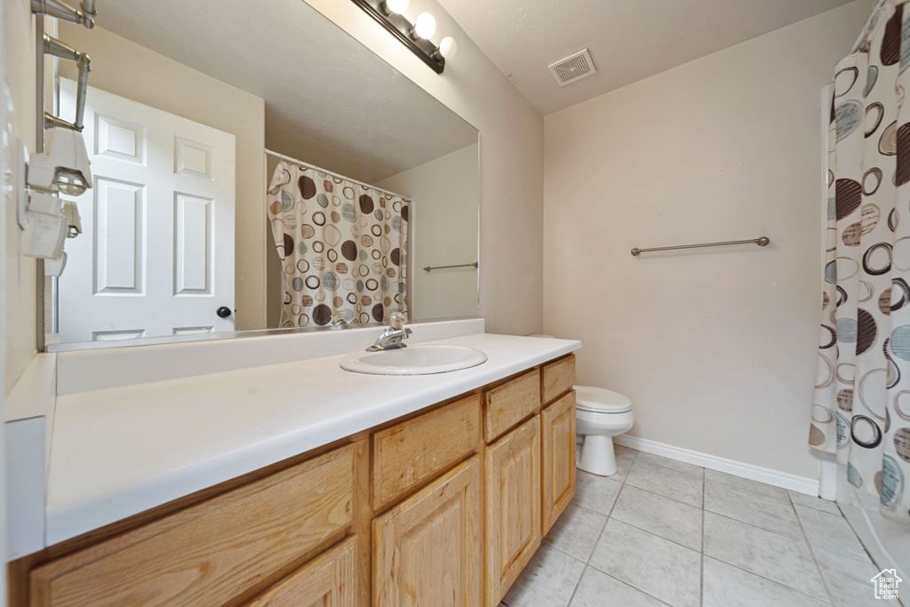 Full bath featuring toilet, vanity, tile patterned flooring, a shower with shower curtain, and baseboards