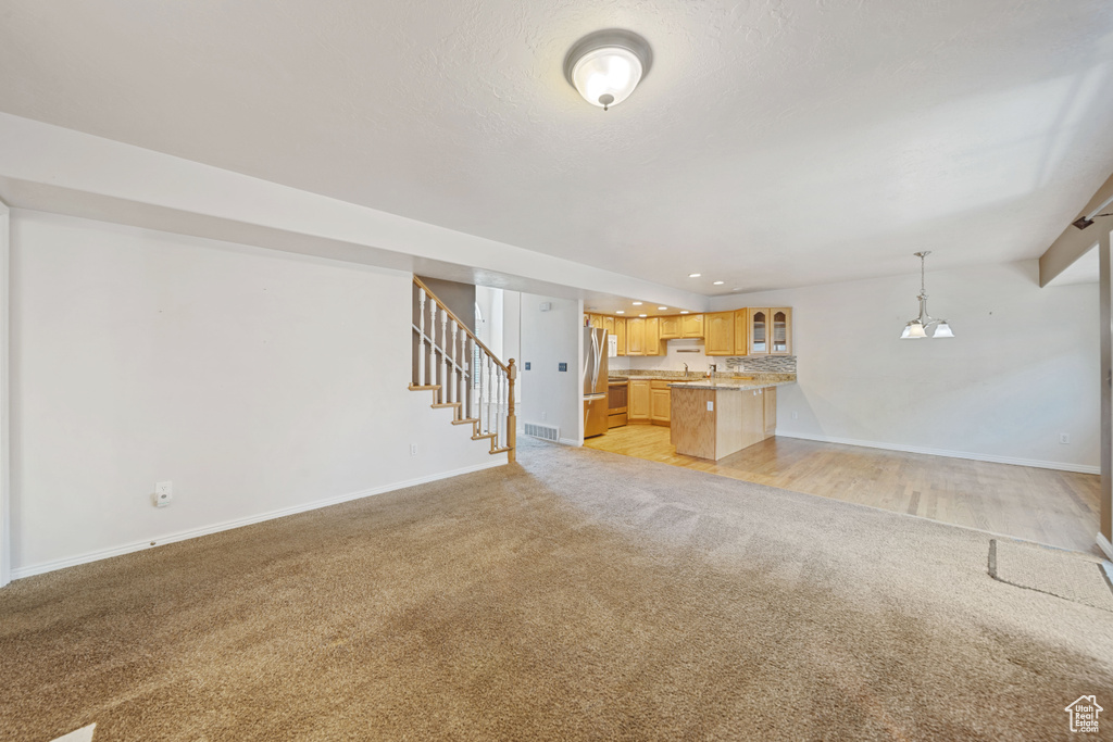 Unfurnished living room with light colored carpet, baseboards, stairway, and recessed lighting