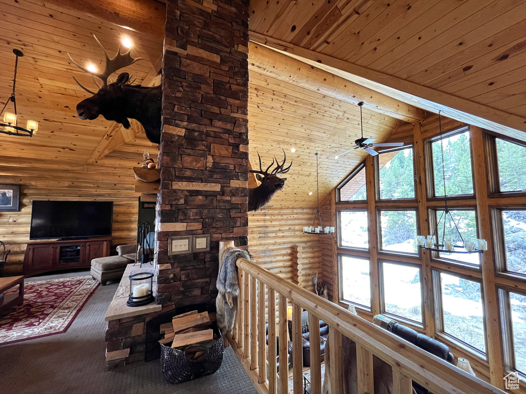 Living room featuring rustic walls, high vaulted ceiling, wood ceiling with exposed beams, carpet flooring, and ceiling fan