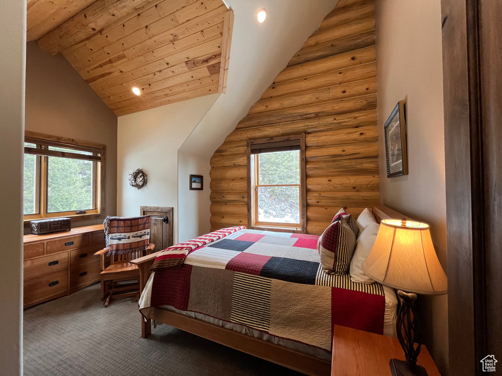 Bedroom with high vaulted ceiling, rustic walls, multiple windows, carpet floors, and wood ceiling