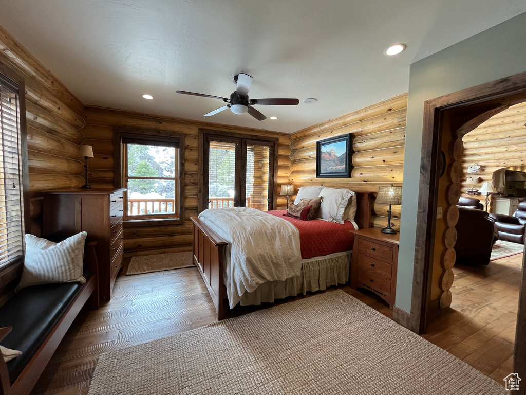 Bedroom featuring rustic walls, wood-type flooring, recessed lighting, and ceiling fan