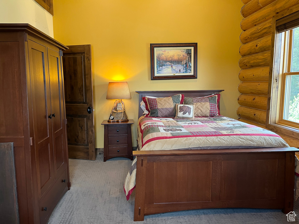 Bedroom featuring log walls, carpet floors, and multiple windows
