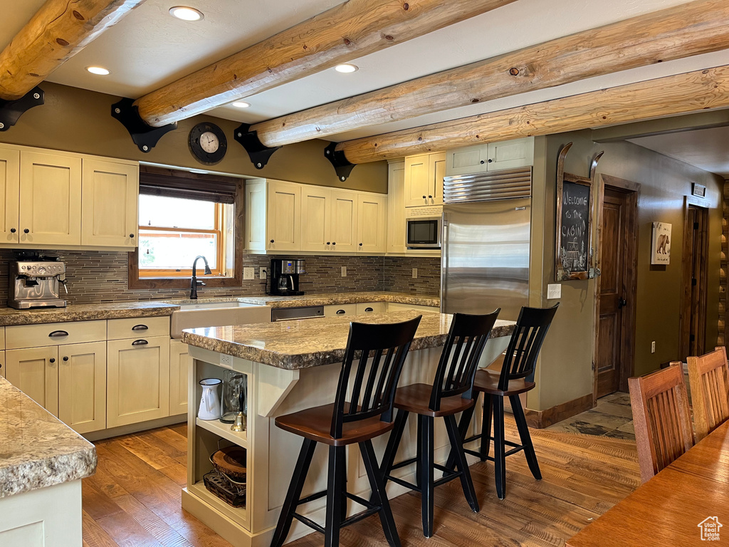 Kitchen with a sink, recessed lighting, wood finished floors, appliances with stainless steel finishes, and a kitchen breakfast bar