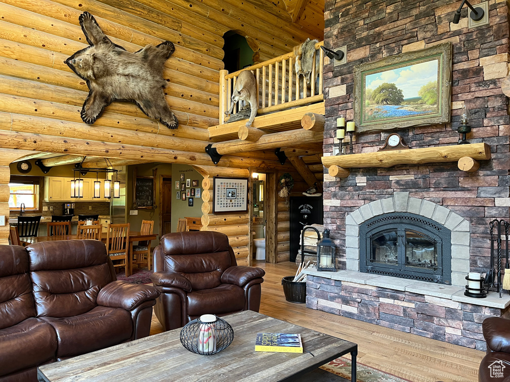 Living area with log walls, wood finished floors, and a fireplace