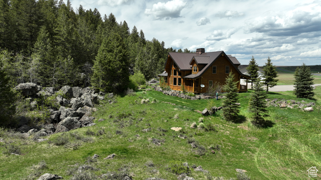 View of property exterior featuring a chimney, metal roof, and log exterior