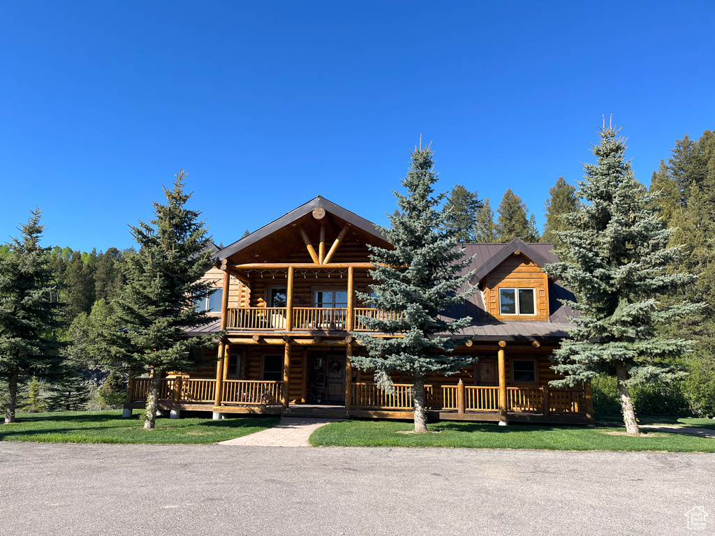 Cabin with covered porch, a balcony, and log siding