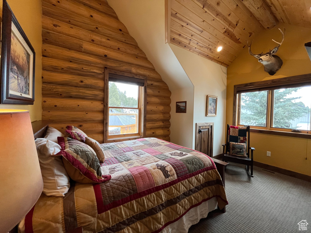 Carpeted bedroom with log walls, baseboards, and wood ceiling