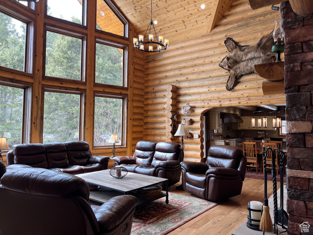 Living area with high vaulted ceiling, hardwood / wood-style flooring, a chandelier, wood ceiling, and log walls