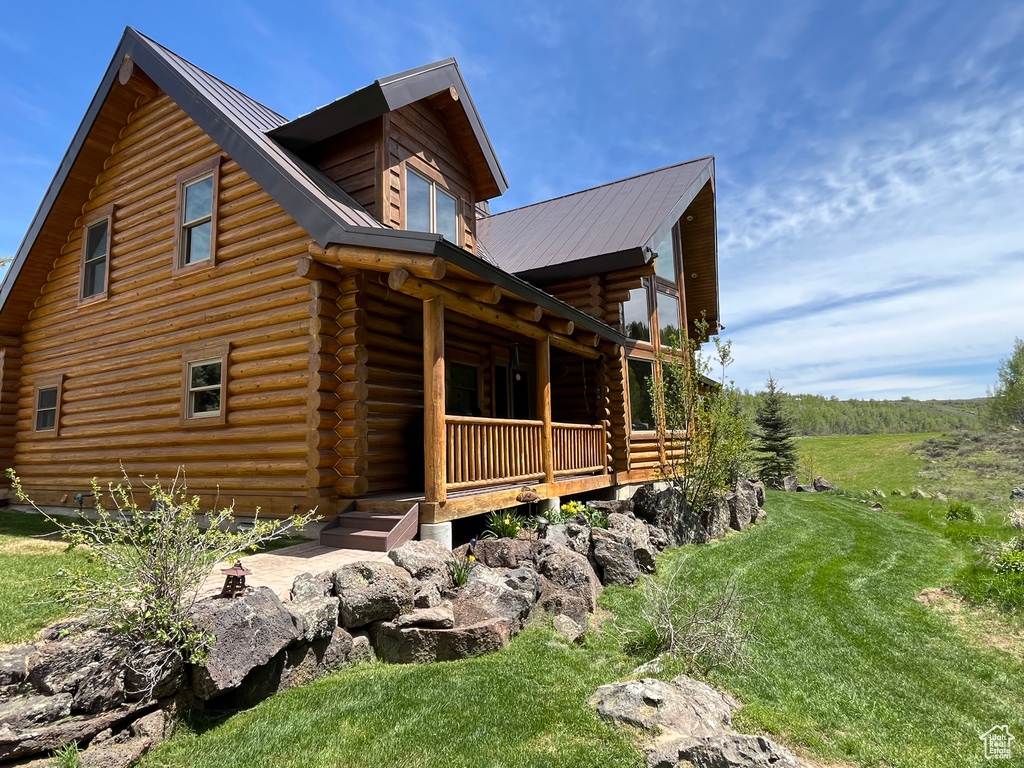 View of home's exterior featuring log exterior, a porch, and metal roof