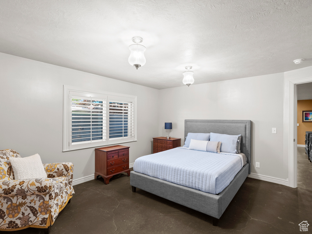 Bedroom featuring concrete flooring and baseboards