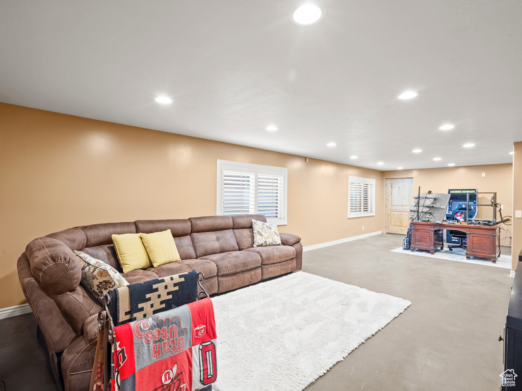 Living room featuring baseboards, recessed lighting, and finished concrete flooring