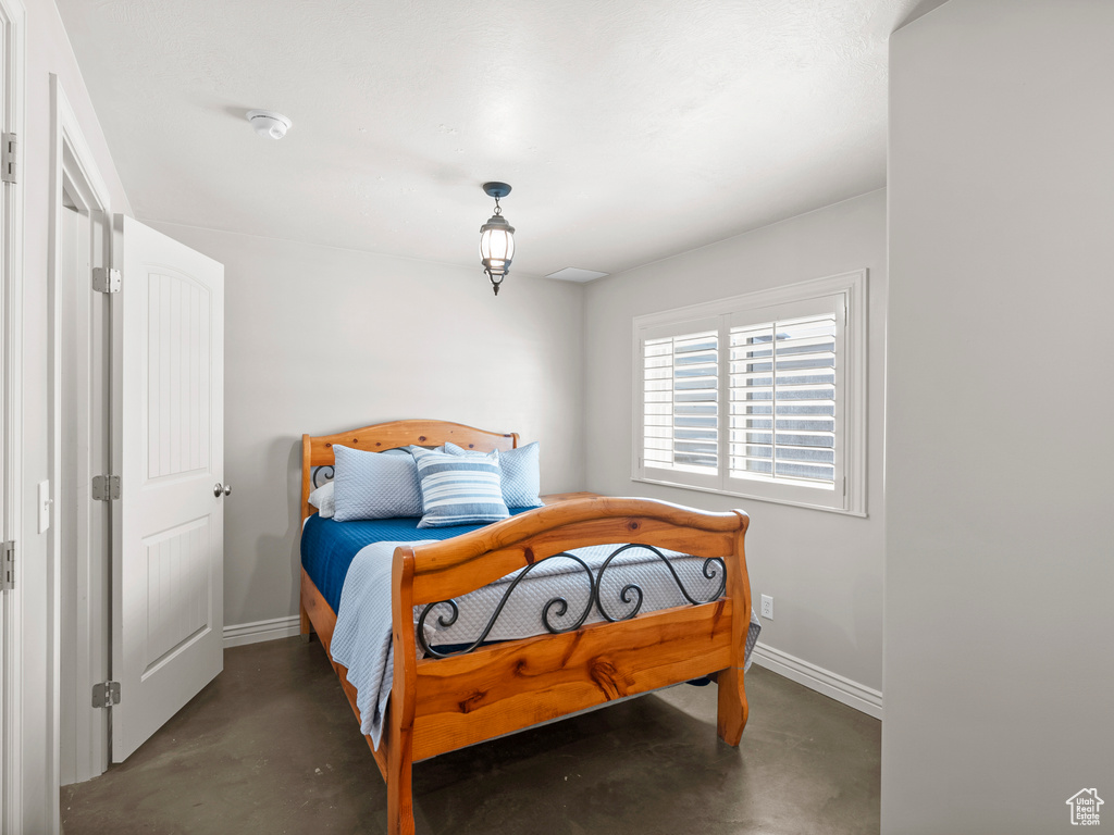 Bedroom featuring concrete flooring and baseboards