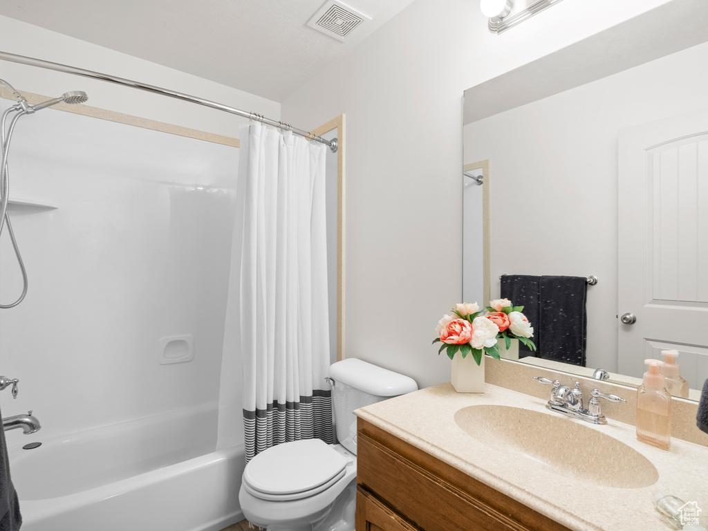 Bathroom featuring shower / bath combo, vanity, and toilet