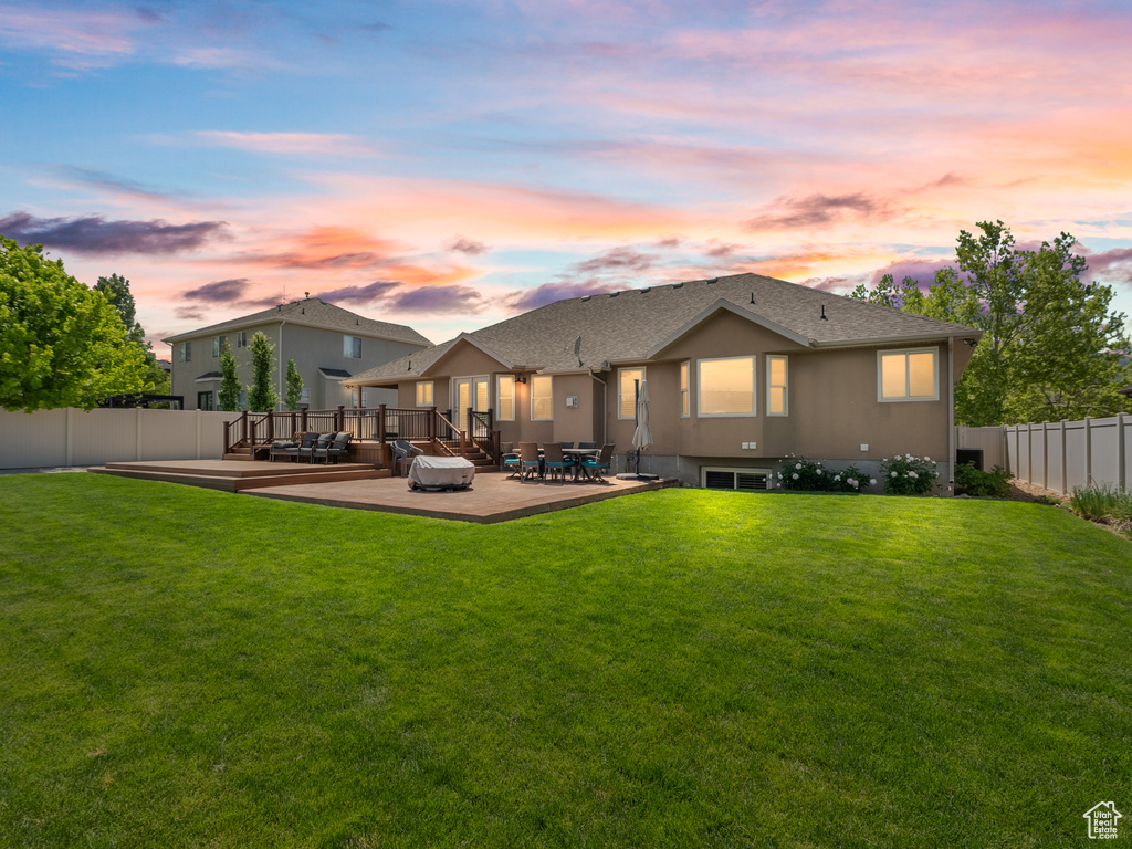 Back of house with a wooden deck, roof with shingles, and a patio
