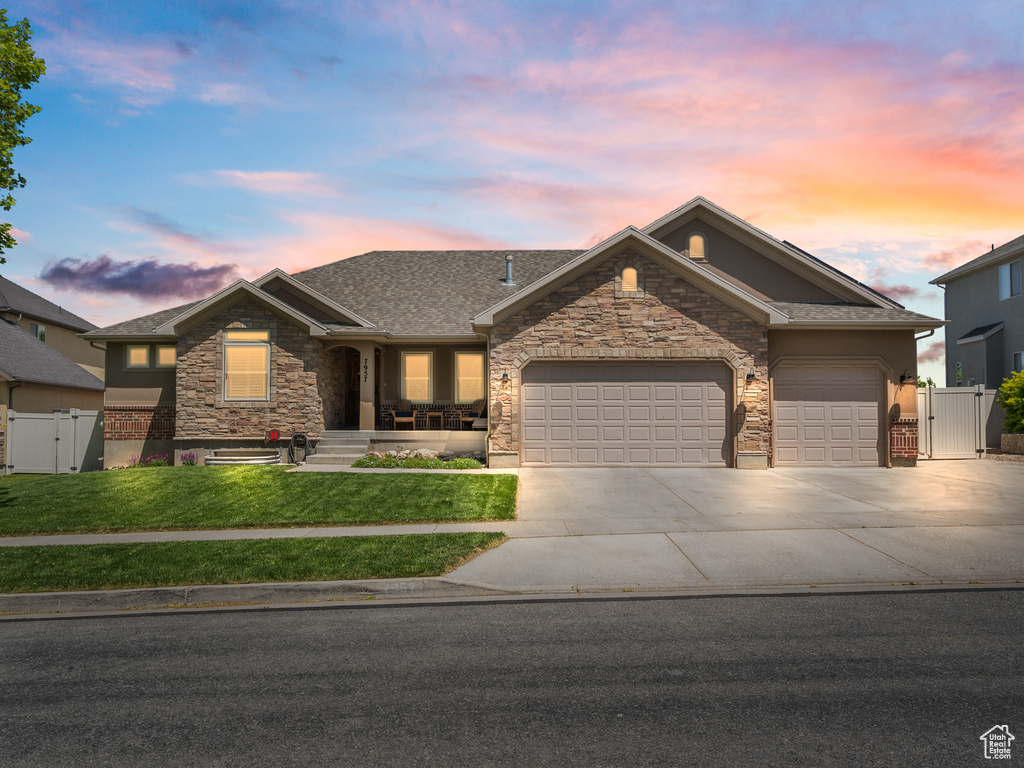 View of front of property with a gate, an attached garage, driveway, stone siding, and roof with shingles