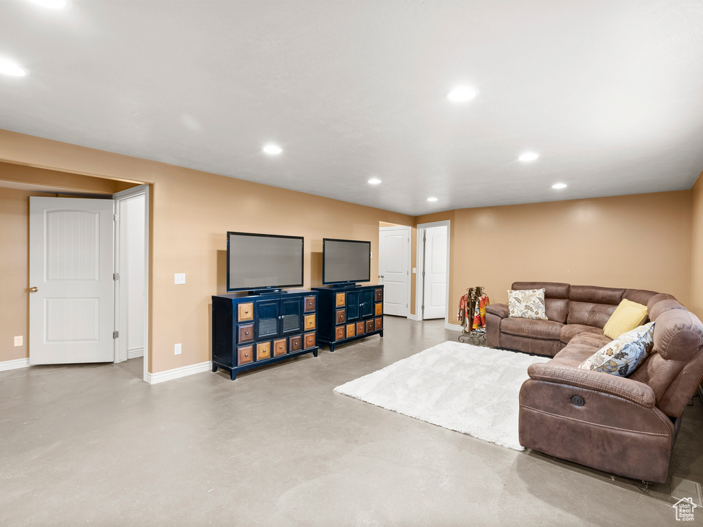Living area featuring finished concrete flooring, baseboards, and recessed lighting