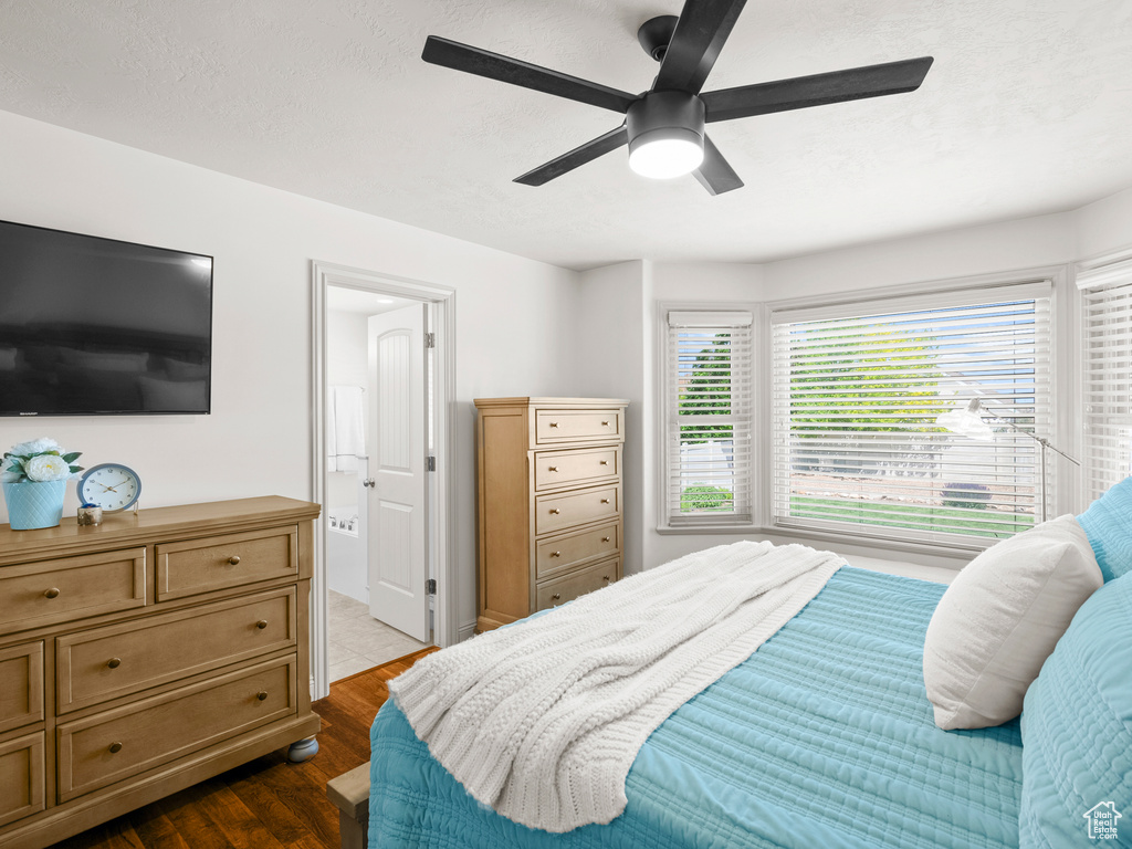 Bedroom with dark wood finished floors, ensuite bath, and ceiling fan