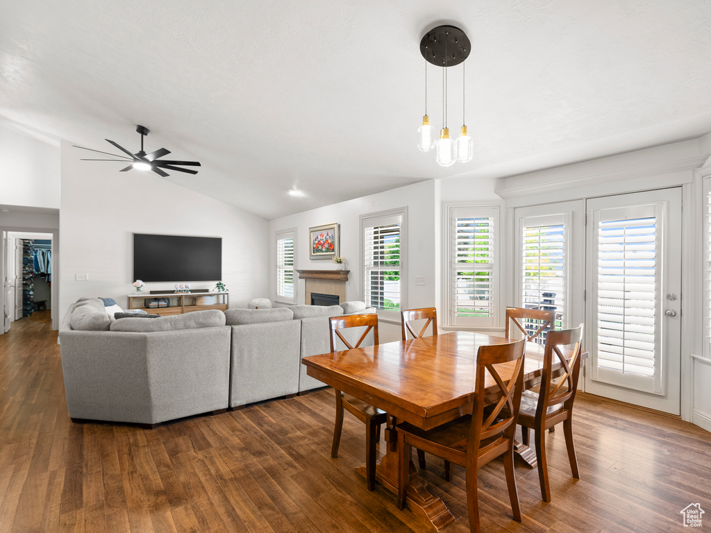 Dining area with vaulted ceiling, dark wood-style floors, a fireplace, and ceiling fan