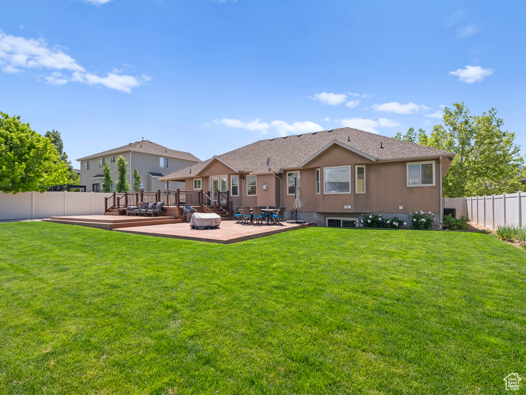 Back of property featuring a wooden deck and stucco siding