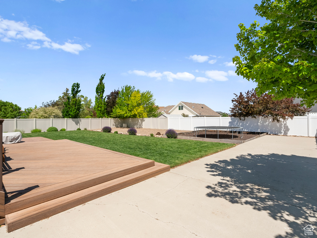 Wooden deck featuring a trampoline and a patio area