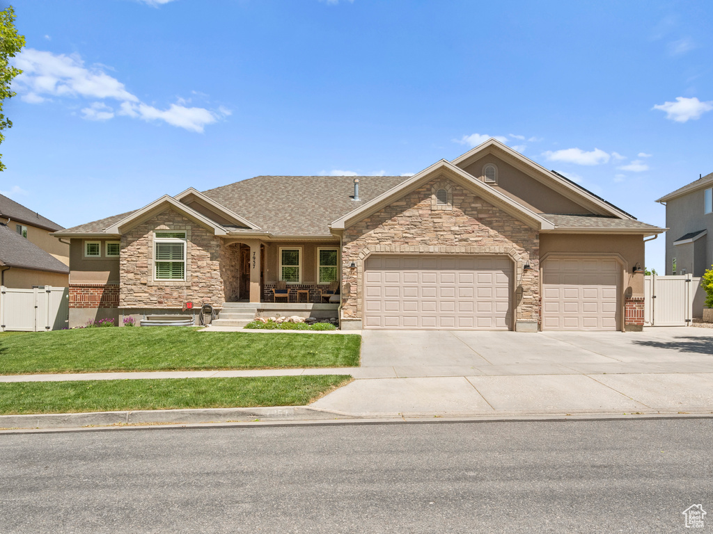 Single story home with a gate, stone siding, an attached garage, and concrete driveway