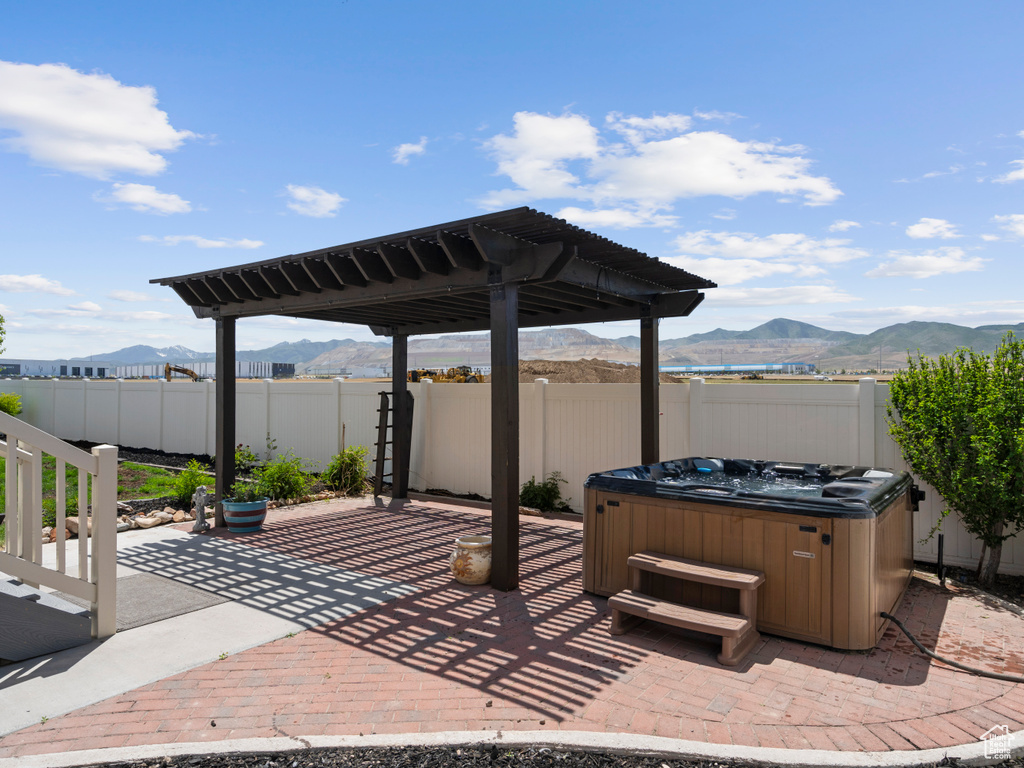 Fenced backyard featuring a hot tub, a mountain view, a patio, and a pergola