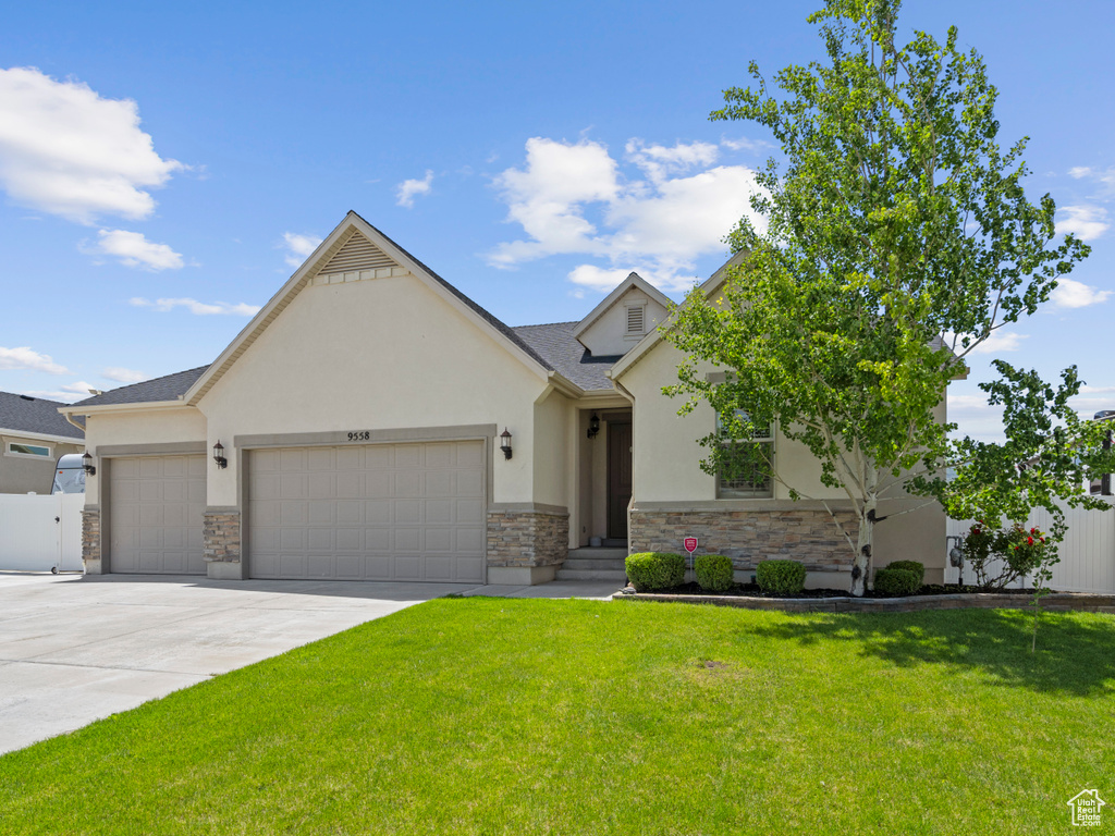 View of front facade with an attached garage, stone siding, stucco siding, and driveway