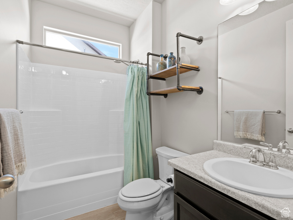 Full bath with toilet, shower / bath combo with shower curtain, vanity, and wood finished floors