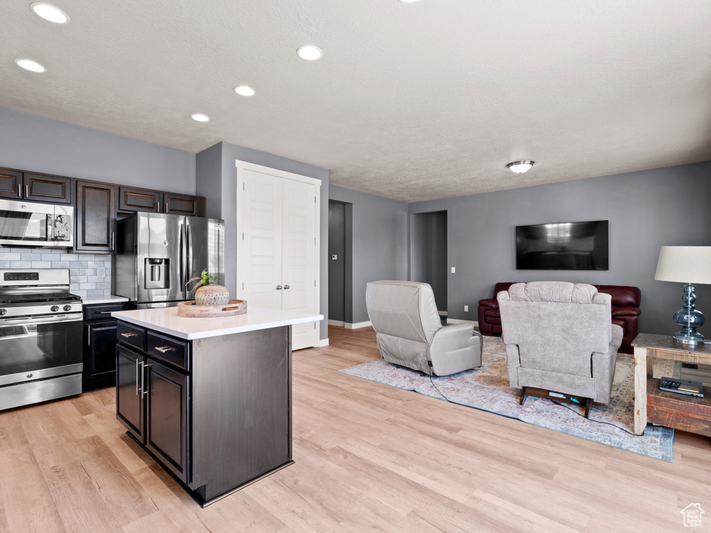Kitchen with appliances with stainless steel finishes, light countertops, light wood-style floors, a kitchen island, and recessed lighting