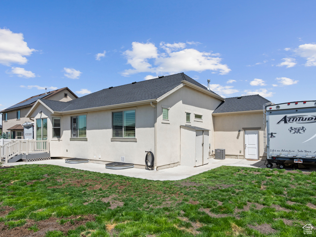 Back of property with cooling unit, stucco siding, a wooden deck, and a lawn
