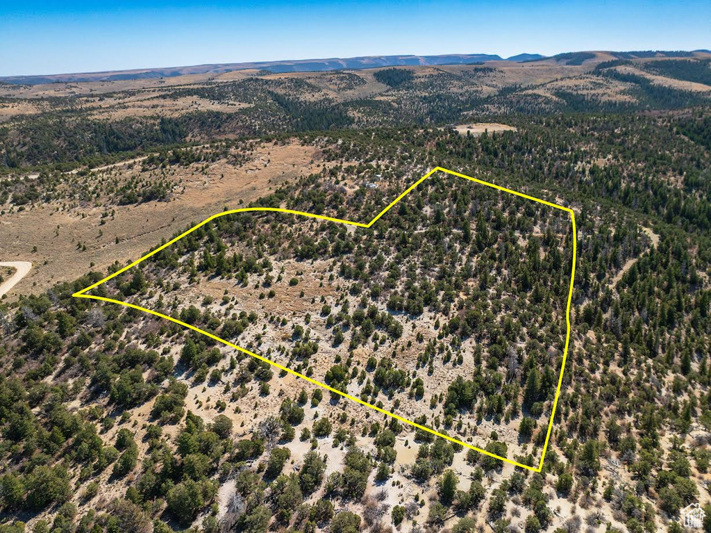 Aerial view of property and surrounding area with property boundaries highlighted and a mountain backdrop
