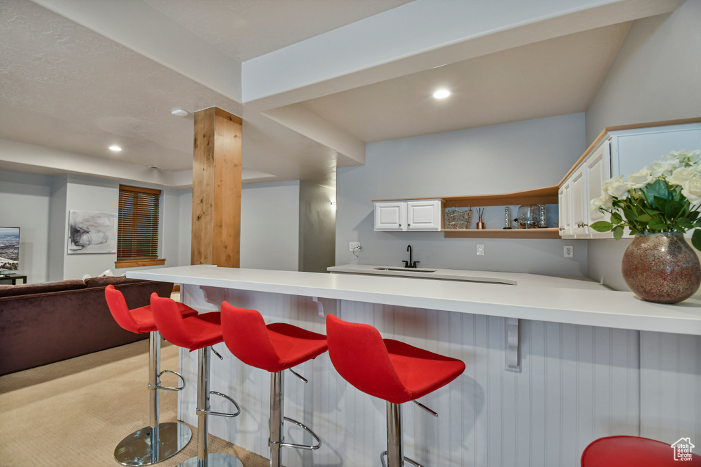 Kitchen featuring light countertops, a kitchen breakfast bar, white cabinets, a peninsula, and recessed lighting