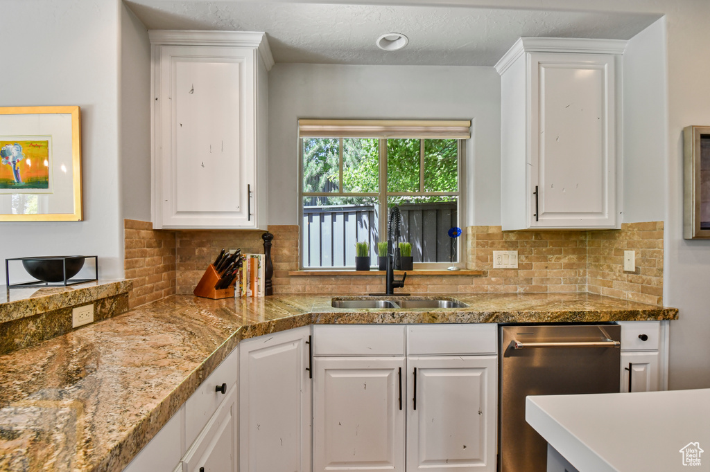 Kitchen with dishwasher, a sink, white cabinetry, backsplash, and a textured ceiling
