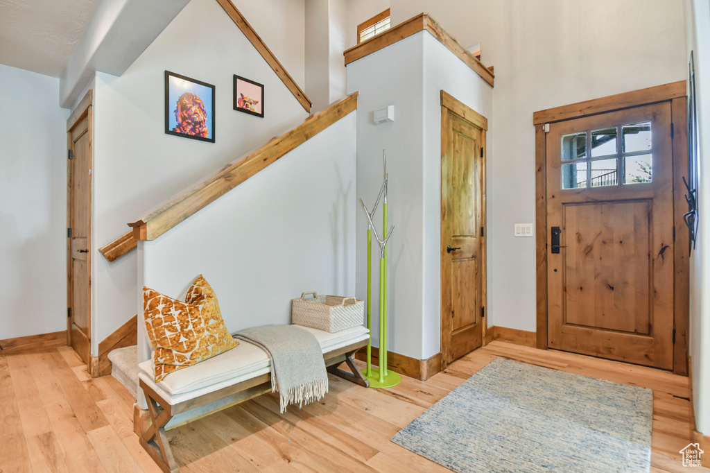 Foyer featuring baseboards, wood finished floors, and stairway