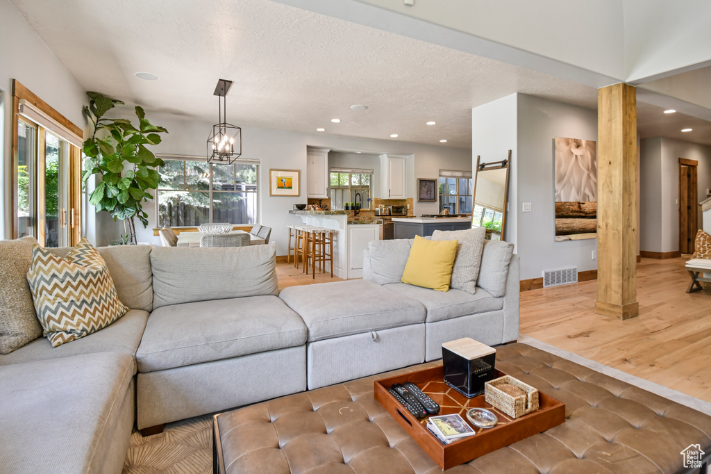 Living room featuring recessed lighting, a chandelier, baseboards, wood finished floors, and a textured ceiling